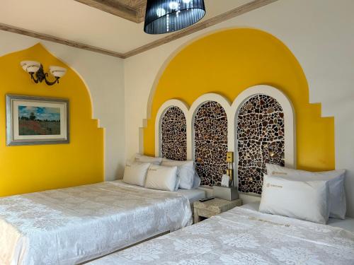 two beds in a room with yellow walls at Empire Motel in Cheonan