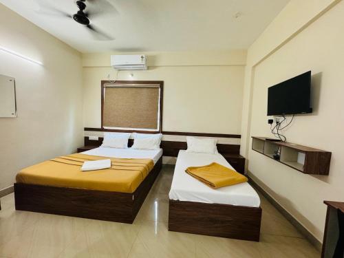 a hotel room with two beds and a flat screen tv at DREAMZ LUXURY HOMe in Kammasandra