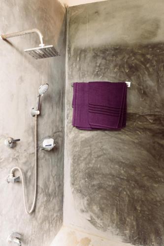 a shower with a purple towel hanging on a wall at Hiriketiya Ladina Homestay in Dickwella