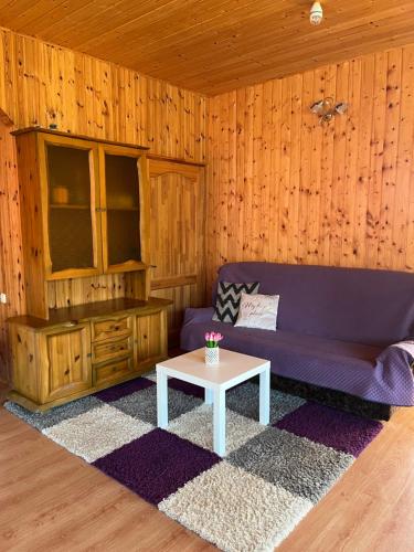 a living room with a purple couch and a table at KRI Holiday House in Alūksne