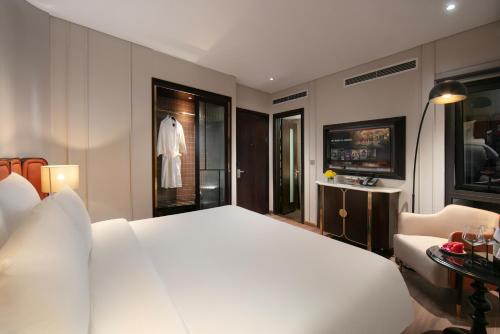 a bedroom with a white bed and a dress in a window at Le Premier Hotel & Rooftop Bar in Hanoi