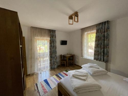 two beds in a room with two windows at Villa Hope (Vila Speranta) in Băile Tuşnad
