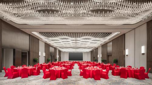 a banquet hall with red chairs and a large chandelier at Holiday Inn Hangzhou GCEC in Hangzhou