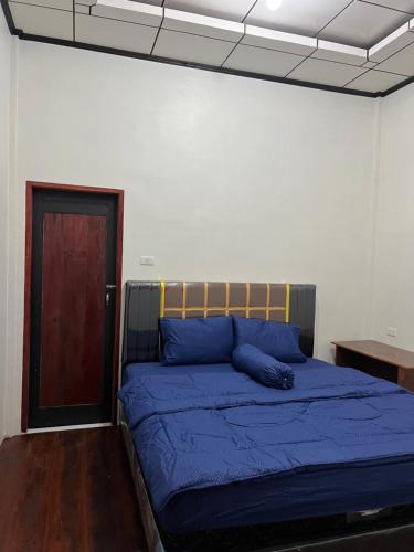 a bedroom with a bed with blue sheets and a door at Para para cafe & cottage in Berastagi