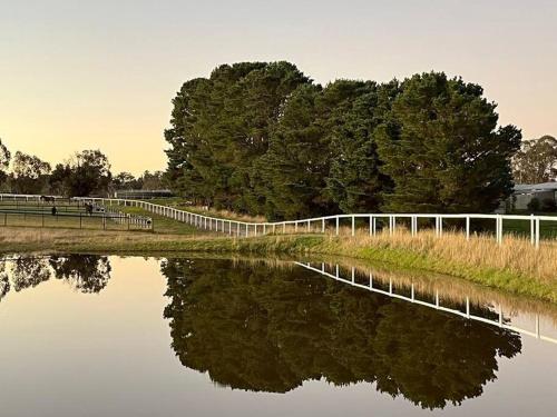 a white fence next to a body of water at Trawalla Farm Stays - Entire House and Large Pool Bar - Perfect for Groups in Bywong
