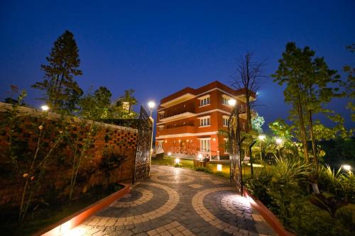 a building with a fence and a brick walkway at night at Kushal Palli Resorts- A unit of PearlTree Hotels & Resorts in Purulia