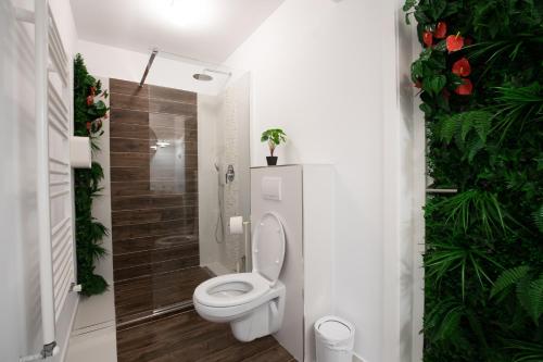 a bathroom with a toilet and a shower with plants at E-House Apartment Brasov in Noua