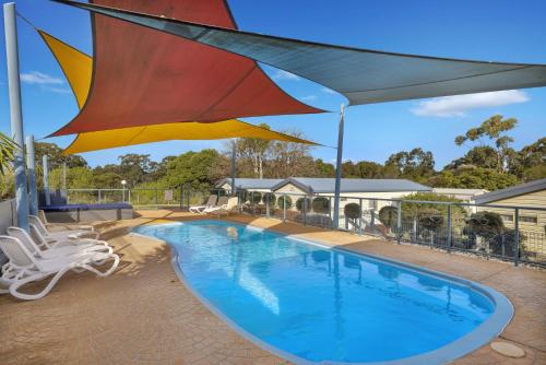 a swimming pool with a large umbrella over it at Metung Holiday Villas in Metung
