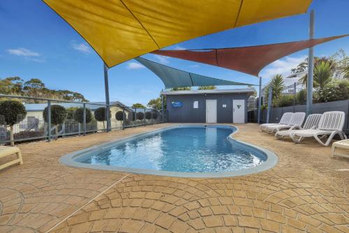 a swimming pool with an umbrella on a patio at Metung Holiday Villas in Metung