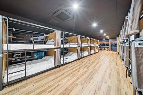 a row of bunk beds in a room with a wooden floor at The Pier Pods on the water- 50m from Townsville bus terminal and ferry terminal- Passport ID requried in Townsville