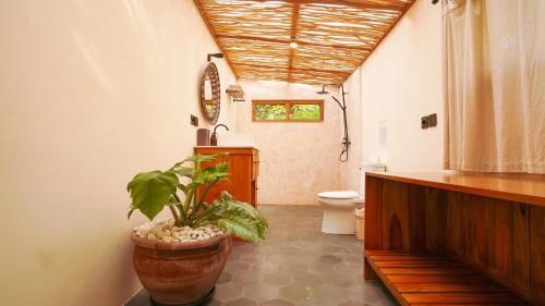 a bathroom with a toilet and a potted plant at Rumah Bambu Gladek Tiga in Uluwatu