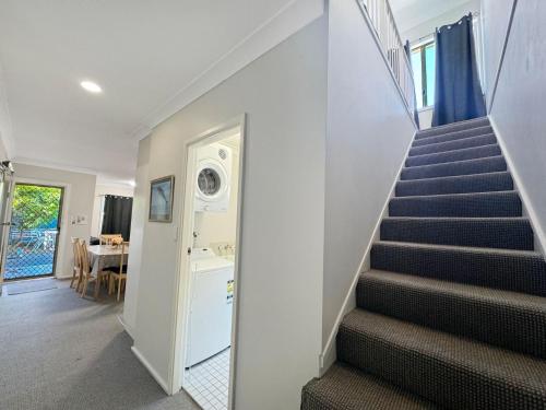 a staircase in a house with a hallway at Opposite Bennetts Beach in Hawks Nest