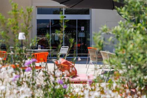 a group of chairs and tables in front of a building at The Originals Boutique, Hôtel Le Pariou, Issoire in Issoire
