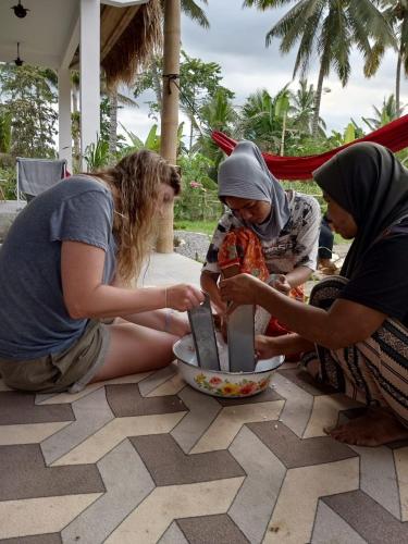a group of three women sitting on the ground eating food at Stay Together in Tetebatu