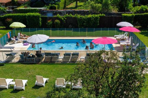 a pool with chairs and umbrellas and people swimming at The Originals Boutique, Hôtel Le Pariou, Issoire in Issoire