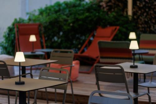 a group of tables and chairs with lights on them at The Originals Boutique, Hôtel Le Pariou, Issoire in Issoire