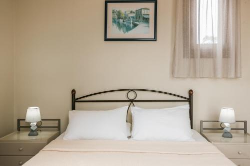 a bedroom with a bed with white sheets and two lamps at Sun Villas in Sarlata