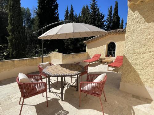une table et des chaises avec un parasol sur une terrasse dans l'établissement La suite du clos de la tour Cassis, à Cassis