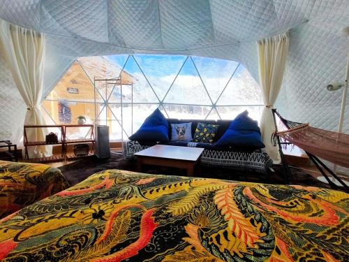 a bedroom with a bed and a large window at 白馬森のわさび農園オートキャンプ場 in Hakuba
