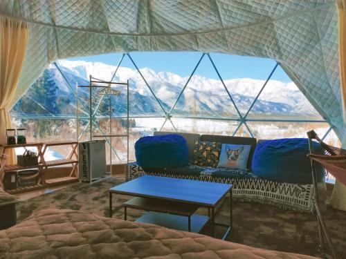 a living room with a couch and a large window at 白馬森のわさび農園オートキャンプ場 in Hakuba