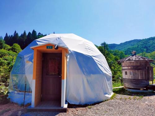 a blue and white tent with a wooden door at 白馬森のわさび農園オートキャンプ場 in Hakuba