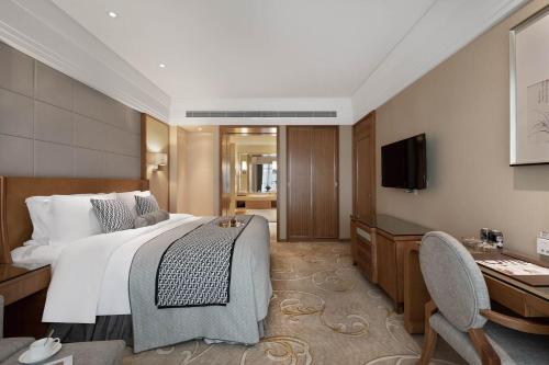 a bedroom with a bed and a desk and a television at Grand Scent Hotel in Chengdu