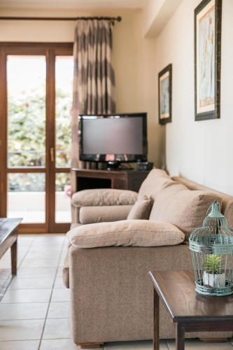 a living room with a couch and a tv at Sun Villas in Sarlata