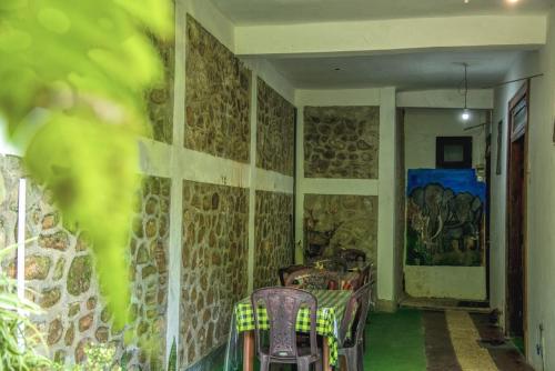 a room with a table and chairs and stone walls at Udessa Rest Ella in Ella