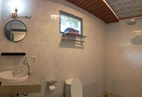 a bathroom with a sink and a toilet and a window at villa meilody 4 - Hera space in Paragajen
