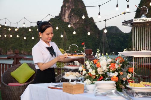 una mujer sosteniendo una bandeja de comida en una mesa en Amanda Halong Cruise, en Ha Long