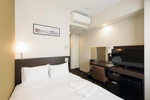 a hotel room with a bed and a flat screen tv at キップホテル湘南藤沢 in Kugenuma