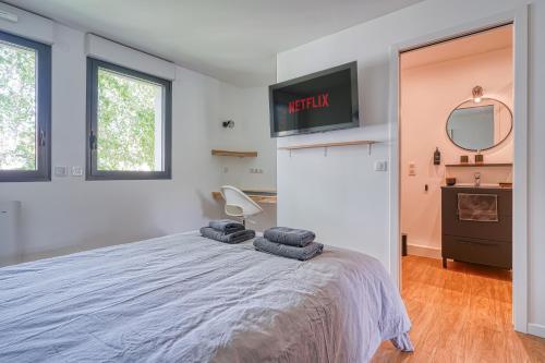 une chambre avec un lit et une télévision au mur dans l'établissement Chambre cosy - cadre verdoyant - proche Saclay, à Gif-sur-Yvette