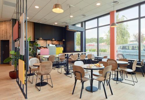 une salle à manger avec tables, chaises et fenêtres dans l'établissement B&B HOTEL Paris Clichy-sous-Bois 3 étoiles, à Clichy-sous-Bois