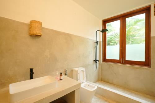 a bathroom with a toilet and a sink and a window at KoLac Villa in Elagawagoda