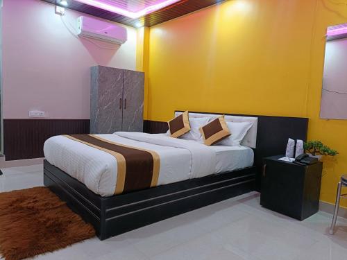 a bedroom with a large bed with yellow walls at Hotel Infinity in Rājgīr