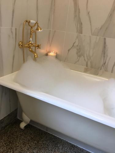 La salle de bains est pourvue d'une baignoire avec bougie. dans l'établissement Le 1930, chambres d’hôtes de charme, à Cosne Cours sur Loire