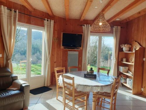 une salle à manger avec une table et des chaises et une télévision dans l'établissement Maison plain pied intérieur bois - Lac de chalain - Gîte les 4 saisons, à Marigny