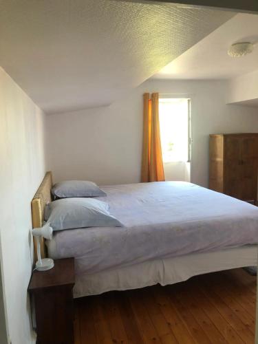 une chambre avec un grand lit avec une fenêtre dans l'établissement Maison charmante à Saint-Germain-de-Lusignan, parking privé, à Saint-Germain-de-Lusignan