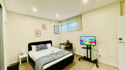 a bedroom with a bed and a flat screen tv at studio near Airpot Bay City in Sydney