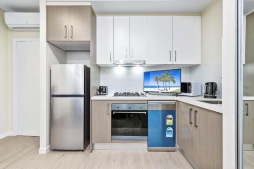 a kitchen with white cabinets and a stainless steel refrigerator at studio near Airpot Bay City in Sydney