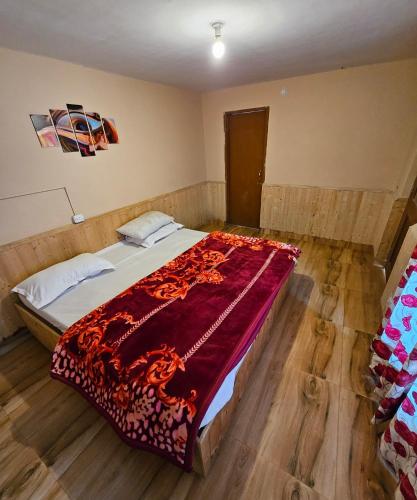 a bedroom with a bed with a red blanket on it at PREMALYA TRAILS By Tirtha in Nagar