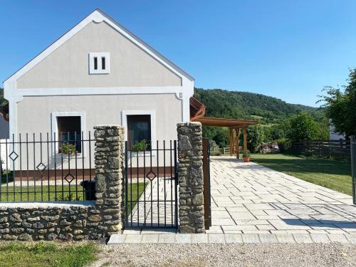 a white house with a gate and a stone wall at Kata Vendégház in Kapolcs