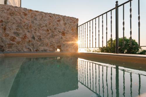 a swimming pool in front of a stone wall at Villa Rosa - Luxury Villas with Panoramic Views in Lagoúdi Zía
