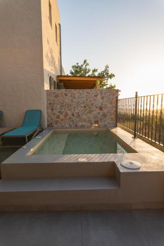 a hot tub on a patio with a blue chair at Villa Rosa - Luxury Villas with Panoramic Views in Lagoúdi Zía