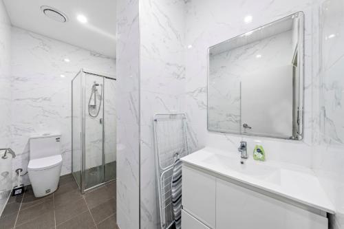a white bathroom with a sink and a mirror at Burwood 1Br apt nearTrainShopping street parking in Sydney