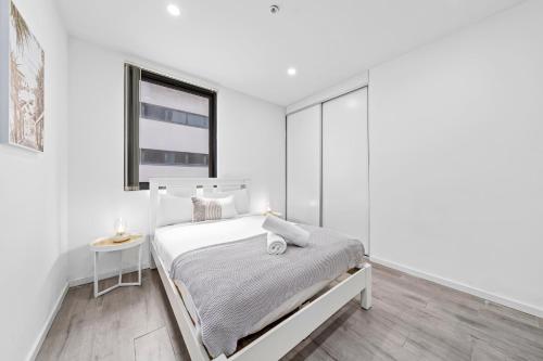 a white bedroom with a bed and a window at Burwood 1Br apt nearTrainShopping street parking in Sydney