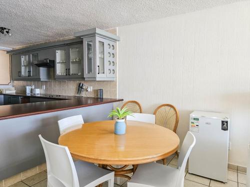 a kitchen with a wooden table and white chairs at Beachcombers 13 in Ballito