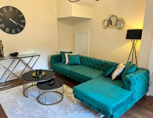 a living room with a green couch and a clock at 3 Bed - Sleeps 7 - Free Parking - Central Location in Glasgow