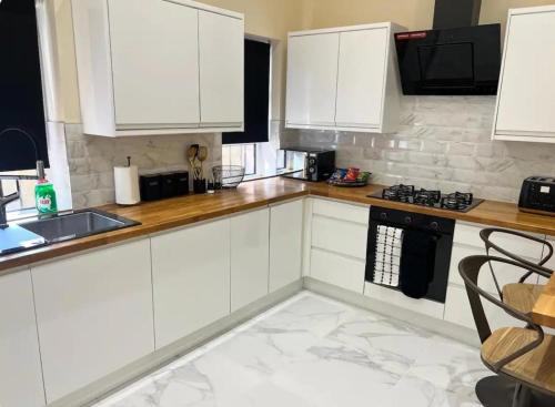 a white kitchen with white cabinets and a sink at 3 Bed - Sleeps 7 - Free Parking - Central Location in Glasgow