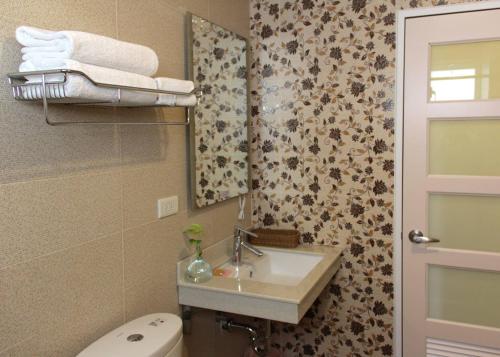 a bathroom with a sink and a toilet and a mirror at HANA Homestay in Taitung City